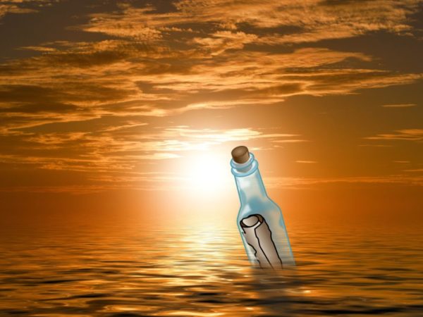 message in a bottle floating on the ocean at sunset